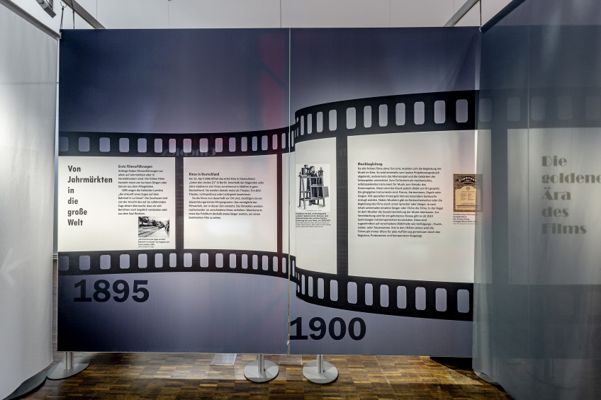 Zwei hochformatige Textilspannwände mit grafischer Filmspule und Text.