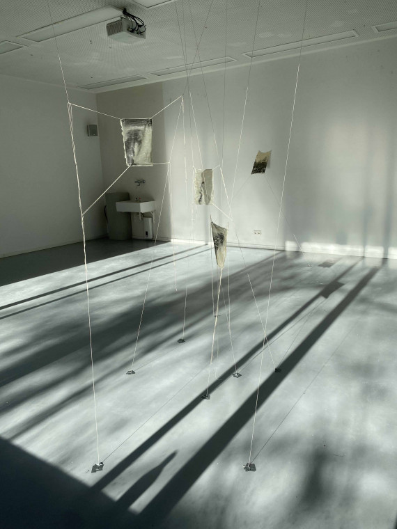 Rauminstallation mit Fäden in weißem Raum.